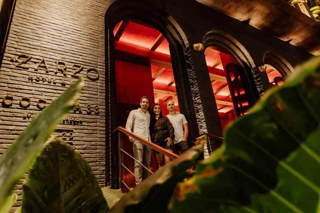 La entrada del restaurante iluminada por la noche, creando un ambiente acogedor y atractivo.