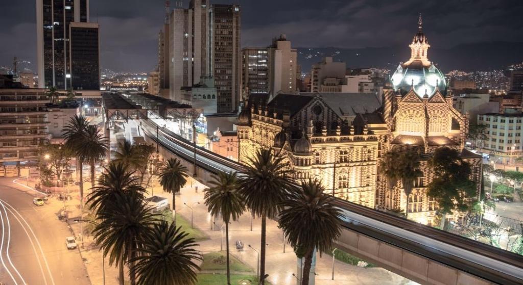 Vista de Medellín de noche calle urbana mientras un tren se desplaza