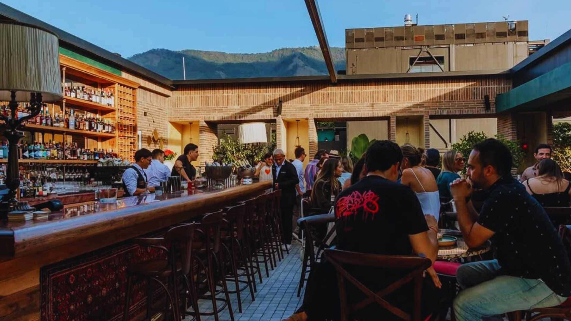 Personas sentadas en un bar de un restaurante, con montañas visibles al fondo.