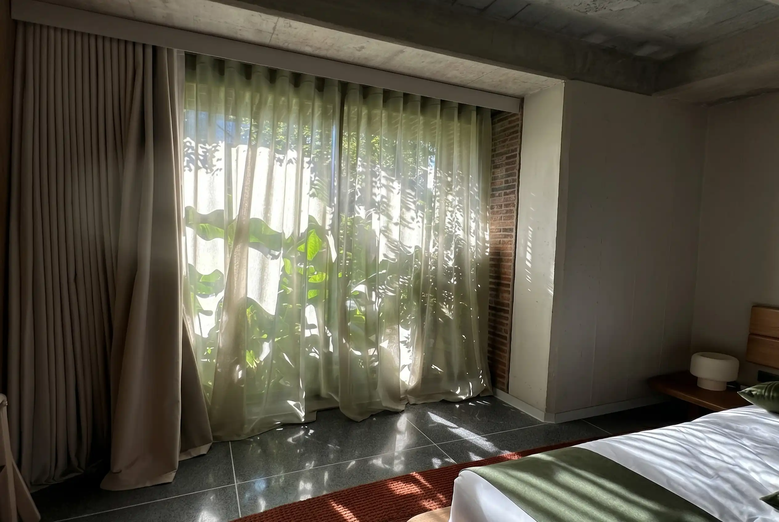 Habitación de Hotel El Zarzo con luz de mañana filtrando por cortinas, antes del brunch en Provenza.