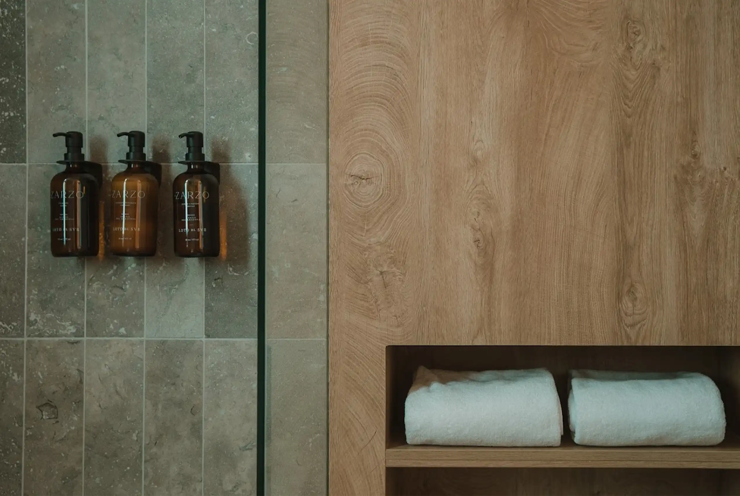 Dispensadores de amenities ZARZO y toallas en baño sostenible de Hotel El Zarzo, Medellín.