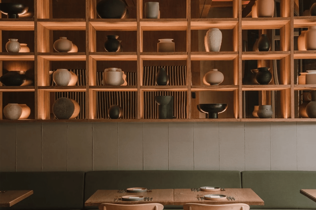 Interior de restaurante en El Poblado con estantería de madera y piezas de cerámica.