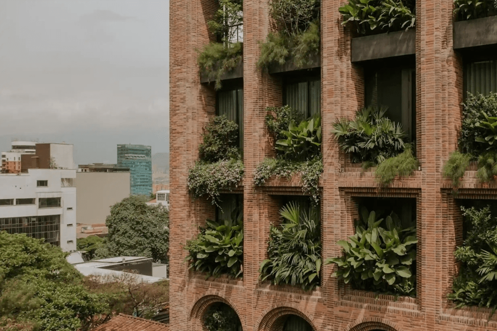 Fachada en ladrillo con jardines verticales escalonados y vista al skyline de El Poblado Medellín.